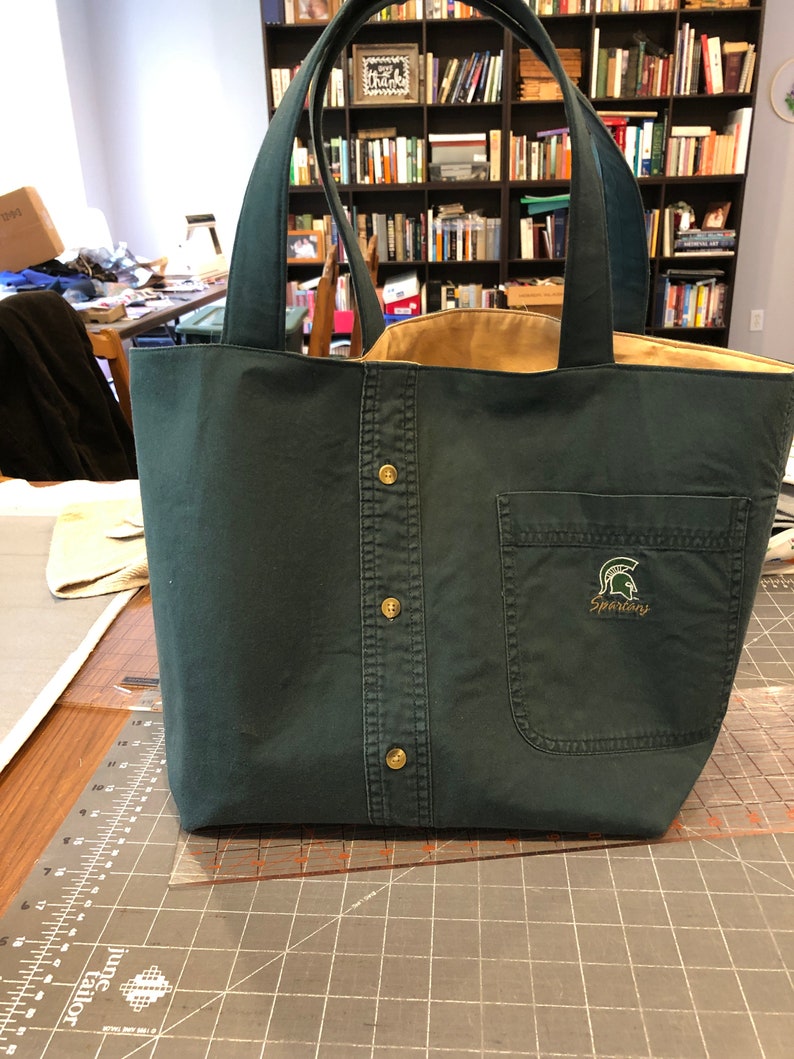 Small tote bag made from a men's button-down shirt. Bag depicted is from a green shirt. Interior of the bag is yellow.