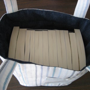 Completed bag can hold about 14 trade paperback books. Bag depicted is white with blue stripes.