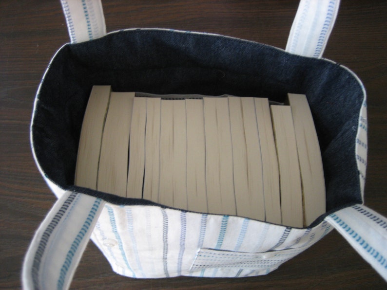 Completed bag can hold about 14 trade paperback books. Bag depicted is white with blue stripes.