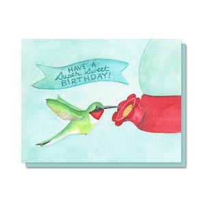 May include: Watercolor birthday card featuring a green hummingbird with a red throat and a long black beak, approaching a red flower. The card has a light blue background and a banner that reads "Have a Super Sweet Birthday!"