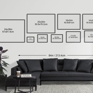 May include: A living room interior design mockup with a black sectional sofa and a black and white coffee table. The wall is decorated with a gallery wall of framed prints in various sizes. The largest print is 24 inches by 36 inches, and the smallest print is 8 inches by 10 inches. The wall is painted white, and the floor is a light gray.