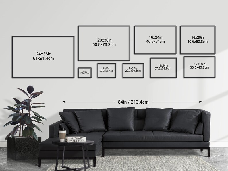May include: A living room interior design mockup with a black sectional sofa and a black and white coffee table. The wall is decorated with a gallery wall of framed prints in various sizes. The largest print is 24 inches by 36 inches, and the smallest print is 8 inches by 10 inches. The wall is painted white, and the floor is a light gray.