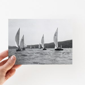 Puede incluir: Fotograf&iacute;a en blanco y negro de veleros en un lago. Varios veleros con velas blancas navegan sobre el agua. La foto est&aacute; sostenida por una mano.