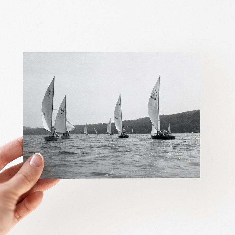 Puede incluir: Fotograf&iacute;a en blanco y negro de veleros en un lago. Varios veleros con velas blancas navegan sobre el agua. La foto est&aacute; sostenida por una mano.