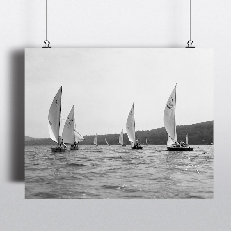 Puede incluir: Fotograf&iacute;a en blanco y negro de varios veleros en un lago. Los barcos tienen velas blancas y navegan en la misma direcci&oacute;n. La imagen es una impresi&oacute;n vintage, con un enfoque en el agua y los barcos.