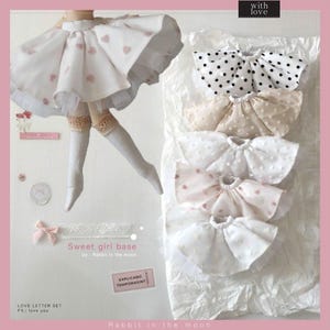 Op de afbeelding: Een set van vijf poppenrokken in verschillende kleuren en patronen, waaronder wit met roze hartjes, wit met zwarte stippen, beige met witte stippen, wit met roze hartjes en wit met witte stippen. De rokken zijn gemaakt van een zachte, delicate stof en zijn perfect om een vleugje whimsy toe te voegen aan de garderobe van elke pop. De tekst "Sweet girl base" en "Rabbit in the moon" is zichtbaar op de afbeelding.