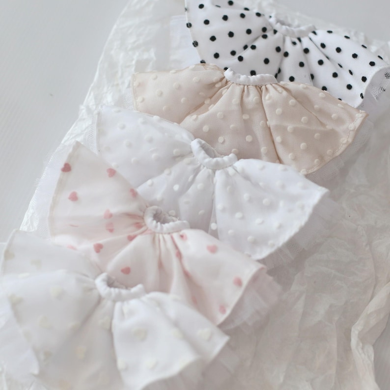 Op de afbeelding: Vijf witte, roze en beige geruite kragen met stippen- en hartjespatronen. De kragen zijn gemaakt van een zachte, delicate stof en zijn perfect om een vleugje whimsy toe te voegen aan elke outfit.