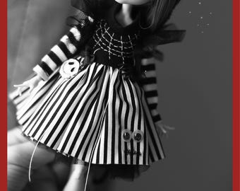 May include: Black and white striped dress with a black bodice and a black tulle overlay. The dress has a spiderweb design on the bodice and a pair of googly eyes on the skirt. The dress is worn by a doll with long black hair.