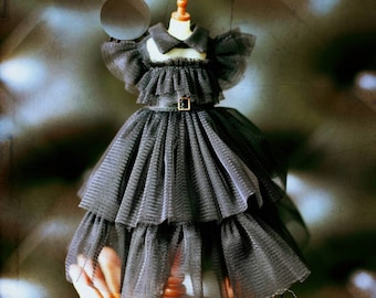 Puede incluir: Un vestido de tul negro con un corpiño con volantes y un cinturón negro. El vestido está en un maniquí y tiene un estilo vintage.