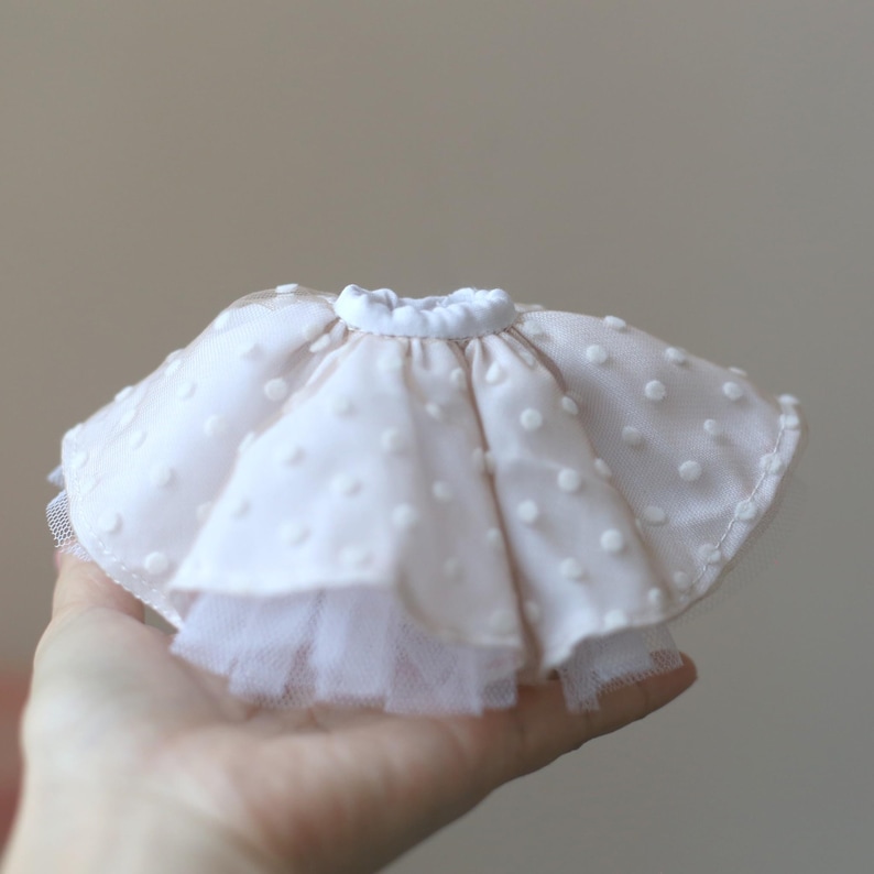 Op de afbeelding: Een witte tule rok met witte stippen en een witte elastische tailleband.