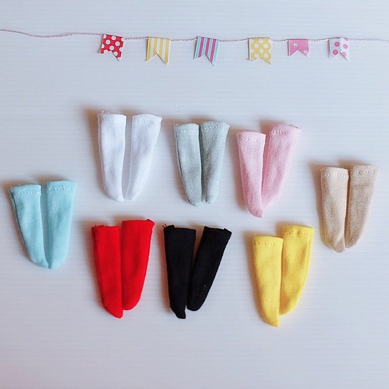 May include: Assortment of ten pairs of colorful doll socks in various colors including white, light blue, light gray, pink, beige, red, black, and yellow.