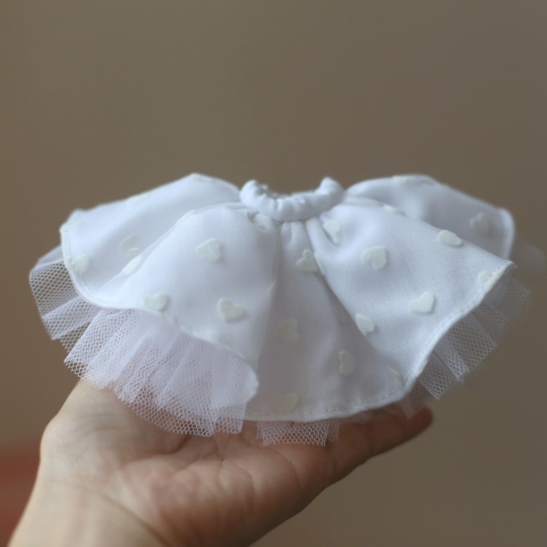 Op de afbeelding: Een witte tule rok met een witte katoenen overlay met een hartjespatroon. De rok heeft een elastische tailleband.