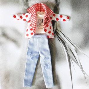 May include: A red and white polka dot jacket with a gingham collar and a white t-shirt underneath. The jacket is paired with light blue denim jeans with distressed details.