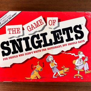 May include: A vintage board game box titled "The Game of Sniglets" on a red background. The box features cartoon illustrations and text that reads "For people who didn't write the dictionary, but should have."