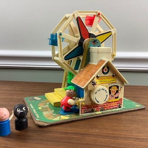 K&ouml;nnte beinhalten: Vintage Fisher-Price Little People Spielset mit einem bunten Riesenrad, einem kleinen Haus mit einem Drehknopf und zwei Little People Figuren. Das Haus hat ein Schild mit der Aufschrift "Fisher-Price Little People Ferris Wheel".