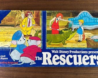 May include: Vintage board game box for "The Rescuers" by Walt Disney Productions. The box features colorful illustrations of cartoon characters, including mice, a woman in a red dress, and a crocodile. The game is for ages 4 to 8 and 2 to 4 players.