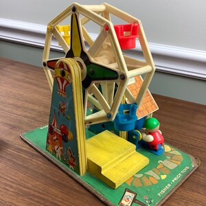 K&ouml;nnte beinhalten: Vintage Fisher-Price Little People Spielset mit einem Riesenrad, einer gelben Plattform, einem blauen und gr&uuml;nen Riesenrad und einem roten und gr&uuml;nen Fahrer. Das Set enth&auml;lt ein Schild mit der Aufschrift "Fun Ride".