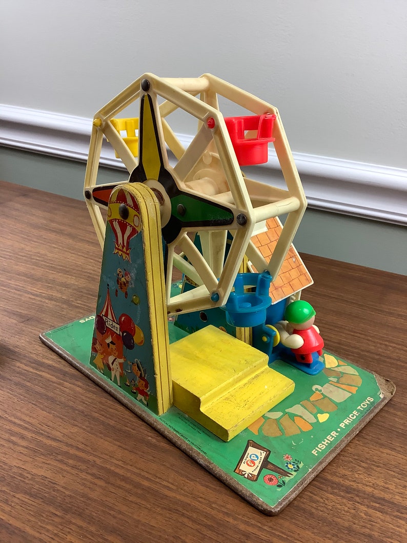 K&ouml;nnte beinhalten: Vintage Fisher-Price Little People Spielset mit einem Riesenrad, einer gelben Plattform, einem blauen und gr&uuml;nen Riesenrad und einem roten und gr&uuml;nen Fahrer. Das Set enth&auml;lt ein Schild mit der Aufschrift "Fun Ride".