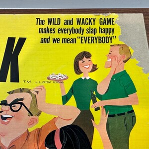 Puede incluir: Caja de juego de mesa vintage con fondo amarillo e ilustraciones de dibujos animados. El texto dice "The WILD and WACKY GAME makes everybody slap happy and we mean 'EVERYBODY'". Presenta un dise&ntilde;o retro con personajes sonrientes.