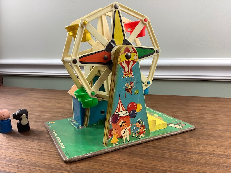K&ouml;nnte beinhalten: Vintage Fisher-Price Little People Spielset mit einem bunten Riesenrad, einem blauen und gelben Hei&szlig;luftballon und einem gr&uuml;n-gelb gestreiften Zelt. Das Set enth&auml;lt eine gr&uuml;ne Basis mit dem Aufdruck "Fisher-Price Toys".