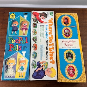 May include: Three vintage children's toy boxes are displayed. The boxes are titled "PeePul Pals", "Where Do I Live? Peek-A-Boo Sewing Cards", and "Lucky Locket Kiddles Magic Paper Dolls". The boxes feature illustrations of dolls and animals.