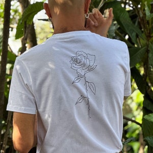 May include: A white t-shirt with a black line drawing of a rose on the back.