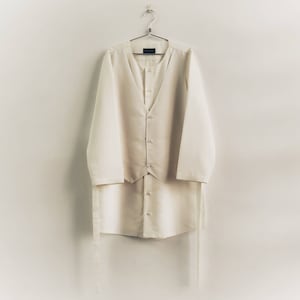 May include: A white long-sleeved shirt with a matching white vest. The shirt and vest have a V-neck and are hanging on a hanger.