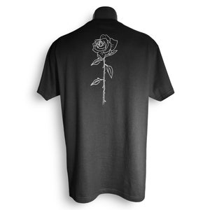May include: Black t-shirt with a white outline of a rose with thorns on the back.