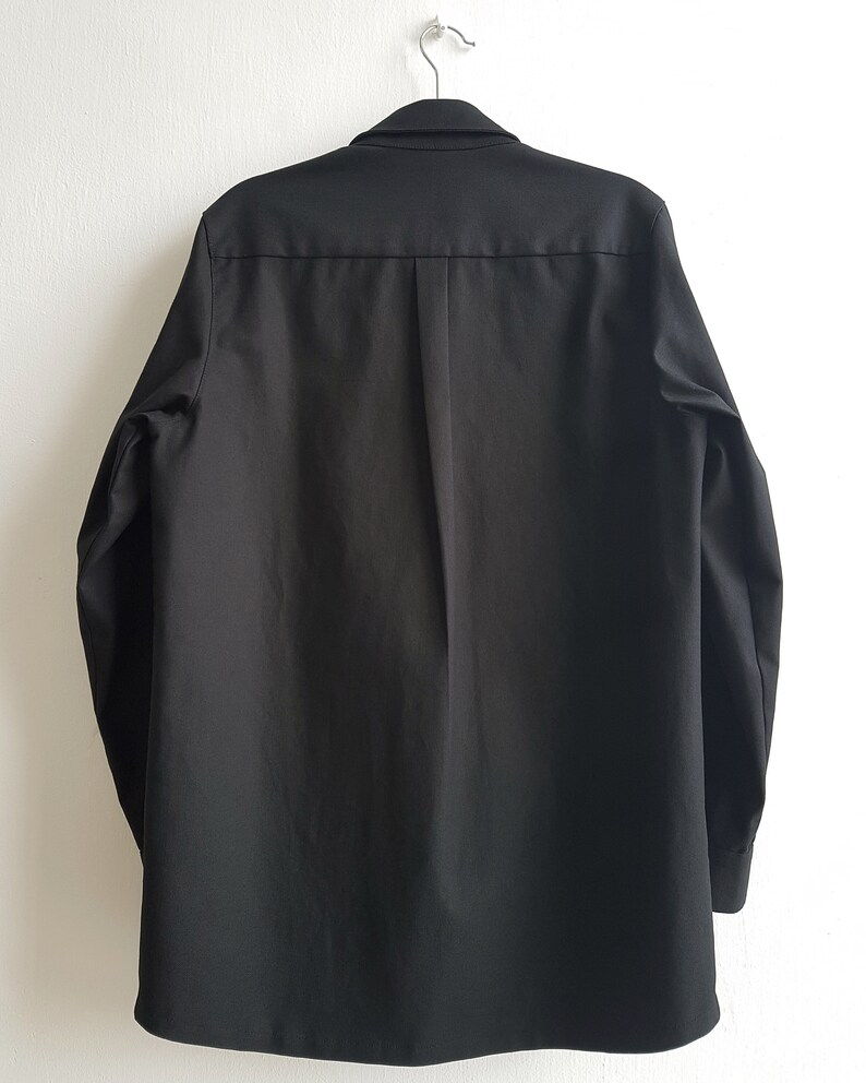 May include: A black long-sleeved button-up shirt with a collar and a single button closure at the top.