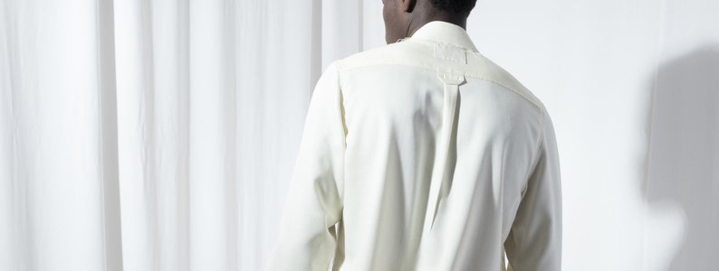 May include: A white long-sleeved shirt with a button-up collar and a single button at the top of the collar.