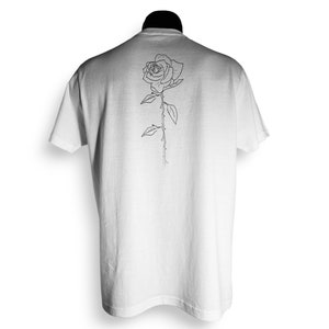May include: White t-shirt with a black line drawing of a rose on the back.