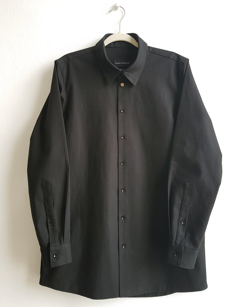 May include: A black long-sleeved button-down shirt with a collar and a label that reads "EURYDICE" on the inside of the collar.