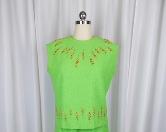 May include: A sleeveless lime green dress with a matching skirt. The dress has a round neckline and is decorated with orange and yellow floral embroidery.