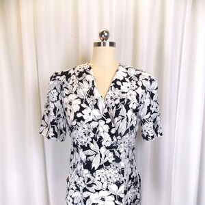 Può includere: Un abito a maniche corte con stampa floreale bianco e nero, scollo a V e chiusura con bottoni.