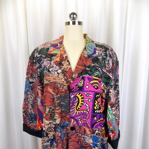 Pode incluir: Um blazer colorido com vários padrões e fecho de botão. O blazer apresenta uma variedade de padrões abstratos e florais em tons de rosa, roxo, laranja, verde e azul.