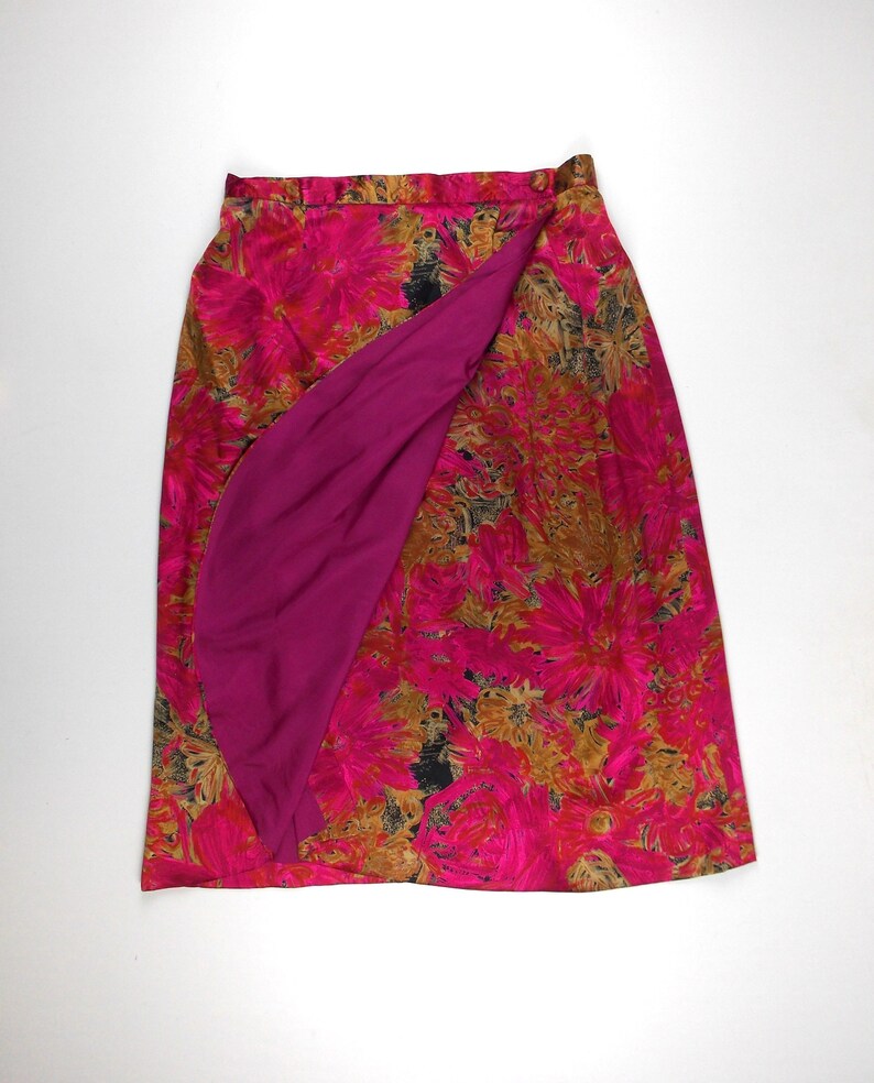 Pu&ograve; includere: Una gonna a portafoglio con stampa floreale rosa e marrone con fodera rosa unita. La gonna &egrave; lunga fino al ginocchio e ha un design semplice.