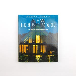 May include: A hardcover book titled Terence Conran's New House Book: The Complete Guide to Home Design. The cover features a photograph of a modern house with large glass windows and warm interior lighting, set against a dark blue sky background.