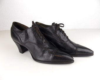 Peut inclure: Une paire de chaussures en cuir noir à lacets, à bout pointu et à talon épais.