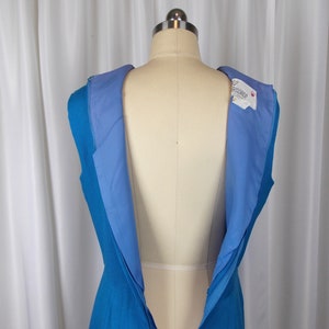 May include: A sleeveless, turquoise blue dress with a light blue lining, displayed on a mannequin. The dress has a visible zipper down the back. A tag with the name "Rothschild" is visible on the inside of the dress.