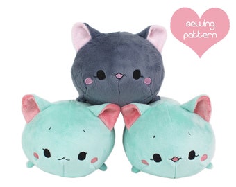 May include: Three plush cat toys in shades of teal and gray, stacked on top of each other. Each cat has pink inner ears, rosy cheeks, and embroidered facial features. A pink heart with the words "sewing pattern" is in the upper right corner.