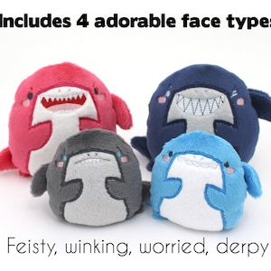 May include: Four plush shark toys with different facial expressions. The sharks are pink, blue, gray, and light blue. The text "Includes 4 adorable face types" is at the top of the image. The text "Feisty, winking, worried, derpy" is at the bottom of the image.