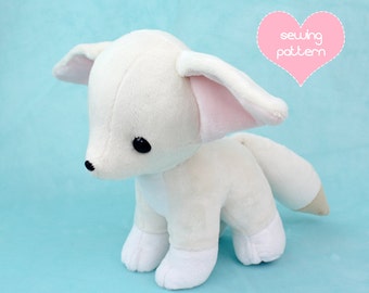 May include: White plush toy fox with pink ears and black eyes. The toy is standing on a light blue background. The text "sewing pattern" is in a pink heart shape in the upper right corner of the image.