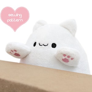 May include: White plush toy shaped like a cat with pink paw prints on its arms and a cute face with black eyes and a small smile. The toy is sitting on a brown surface. The text "sewing pattern" is written in pink on a heart-shaped background.
