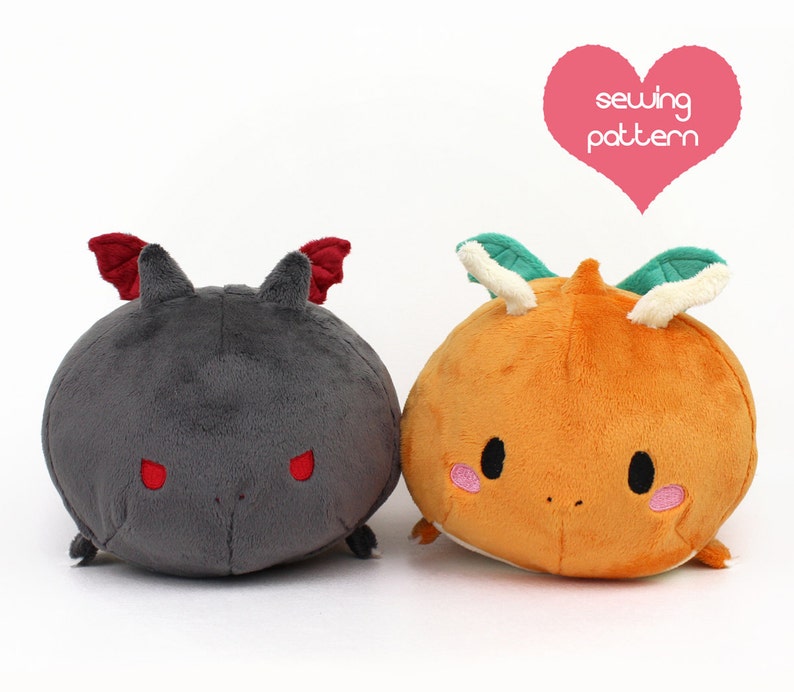 May include: Two plush toys, one gray with red wings and red eyes, and one orange with green leaves and white horns. The toys are both round and have a cute, cartoonish appearance. The text "sewing pattern" is written in a pink heart above the toys.