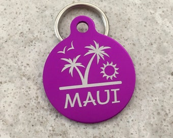 May include: Purple round metal pet tag with a white palm tree and sun design and the word "MAUI" engraved on it.