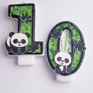 May include: Two green and black panda birthday candles, one shaped like the number 1 and the other shaped like the number 0. Each candle has a panda bear with black eyes and a bamboo stalk.