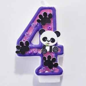 May include: Purple and pink number four birthday candle with a panda bear design. The candle has glitter and paw prints.