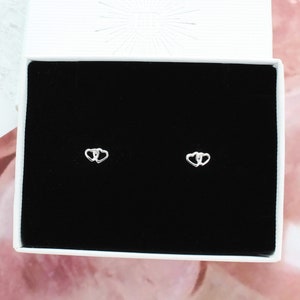 May include: A pair of silver double heart stud earrings in a black velvet jewelry box.