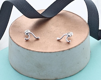 May include: A pair of silver wave earrings. The earrings are small and delicate, and they are perfect for adding a touch of whimsy to any outfit.