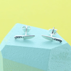 May include: A pair of silver knife earrings. The earrings are in the shape of a knife with a silver blade and a black handle.